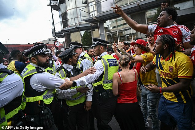 Torcedores turbulentos do Arsenal em confronto com policiais, enquanto um torcedor mostra o dedo médio para eles