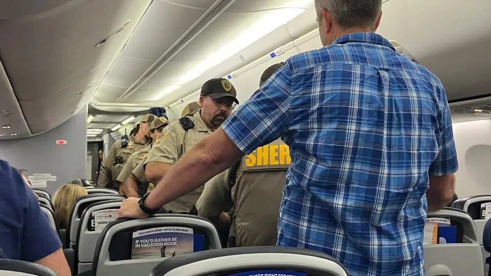 Um passageiro forneceu à CNN uma foto mostrando um homem de camisa azul que ajudou a interpretar o russo durante o incidente. O homem de azul não é o suspeito. - llewynwearsflannels/Reddit